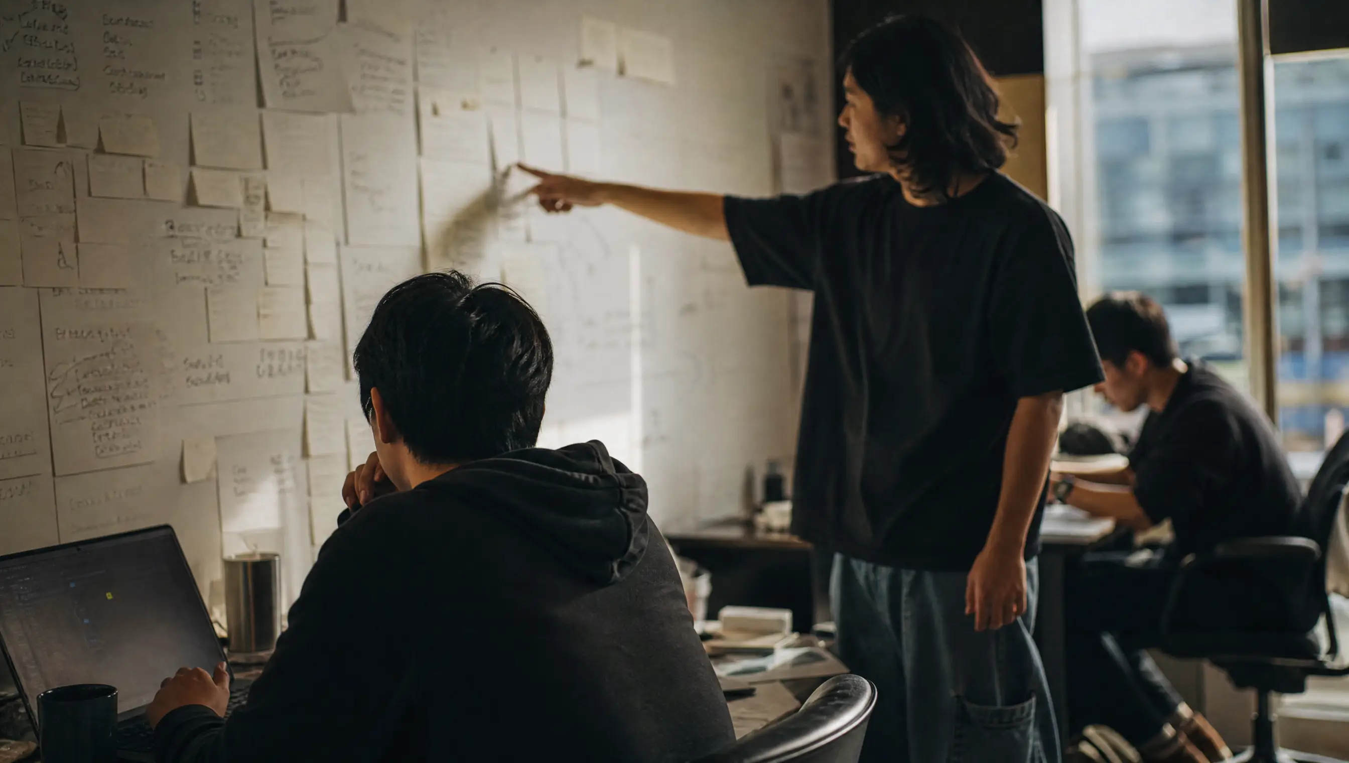 Product team reviewing a wall of strategy notes in a Taipei studio